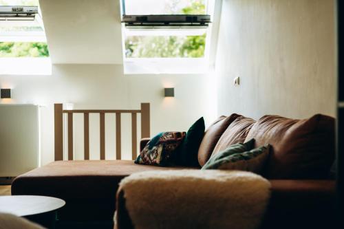 a couch in a living room with two windows at B&B de Vlonder in Stevensweert
