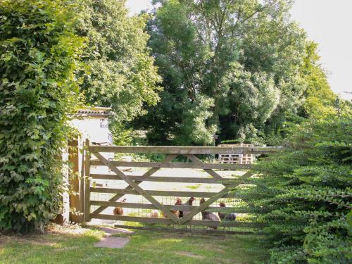 a wooden fence with a gate in a garden at Foxholes Barn in Kidderminster