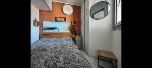 une petite chambre avec un lit et un miroir dans l'établissement APPARTEMENT MODERNE prés de la plage avec parking gratuit, à Frontignan