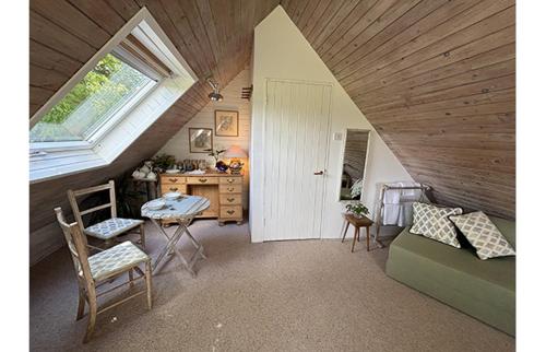 a attic room with a bed and a desk and a window at Brook Barn in Selham