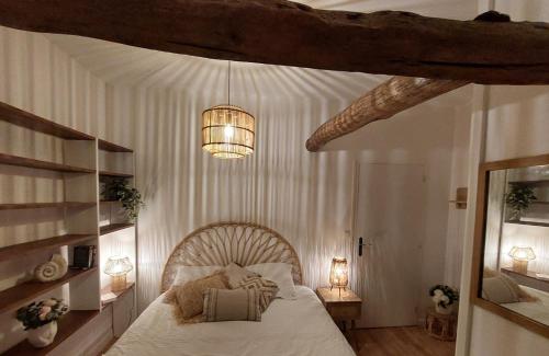 a bedroom with a large bed and a chandelier at La closerie de l'Andelle in Elbeuf-sur-Andelle
