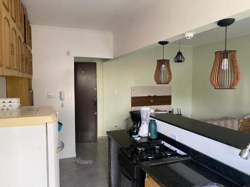 a kitchen with a stove and some pendant lights at Apartamento Centro - Jardim Caiahu - in Mongaguá