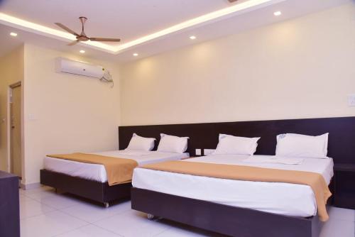 ein Schlafzimmer mit zwei Betten und einem Deckenventilator in der Unterkunft Hotel Devis Velankanni in Velankanni