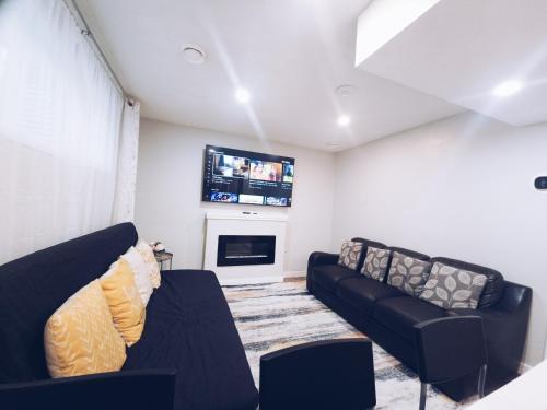 a living room with two black couches and a tv at Cozy 2 Bedroom Suite, Queen Beds, Near the Airport in Edmonton