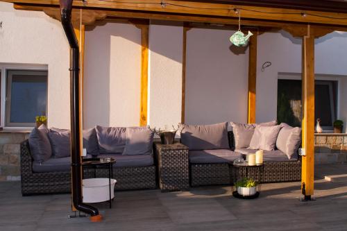a outdoor patio with couches and pillows at Допълнителна къща за гости Ози 2 in Ovchartsi