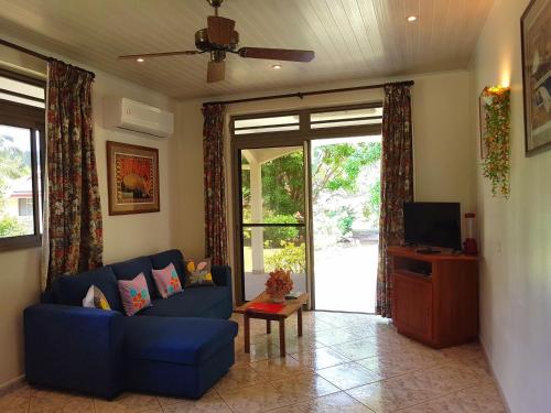 a living room with a blue couch and a tv at HUAHINE - Fare Teakavehere Tipanier in Haapu