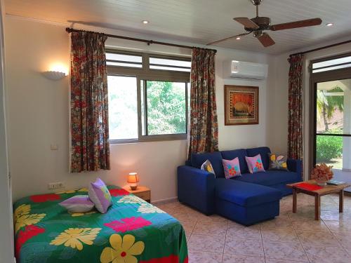a bedroom with a blue bed and a blue couch at HUAHINE - Fare Teakavehere Tipanier in Haapu