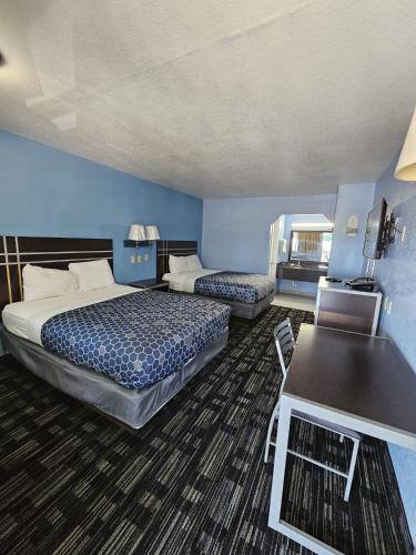 a hotel room with two beds and a table at Regency Inn Motel by the Beach in Corpus Christi