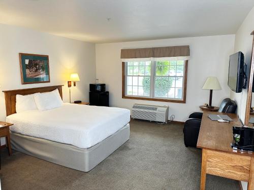 a bedroom with a bed and a desk and a television at Farmstead Inn and Conference Center in Shipshewana