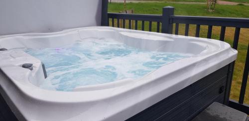 a large bath tub with blue water in it at Holiday Home with a Hot tub in St Austell