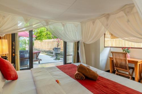 a bedroom with a large white bed with a red blanket at Bali Villa Djodji in Ubud