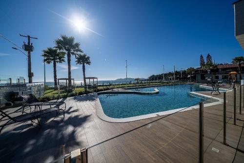 a large swimming pool with palm trees and aitamin at Edifício Solar do Atlântico Beira Mar de Bombas in Bombinhas