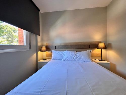 a bedroom with a large white bed with two lamps at SunAndBed ATICO FARO in Salou