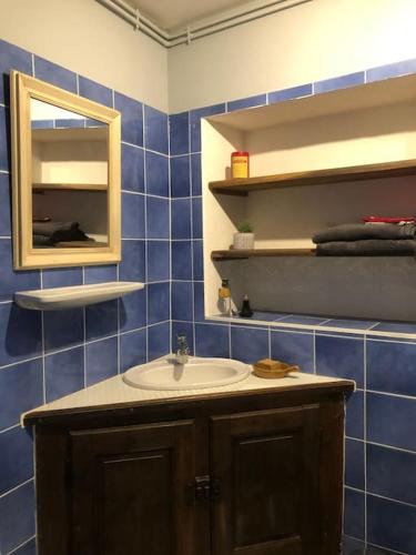 La salle de bains est pourvue de carrelage bleu, d'un lavabo et d'un miroir. dans l'établissement gite Sivry la perche cœur de Logis, à Sivry-la-Perche