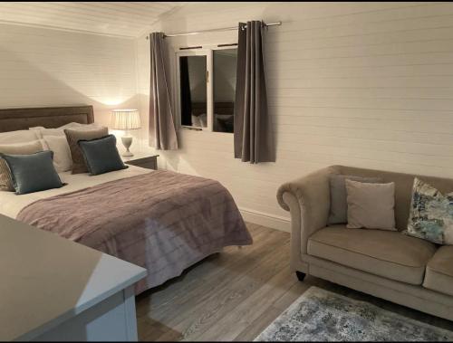 a bedroom with a bed and a couch and a window at Orchard Retreat - Rural Cabin - Private Hot Tub! in Gloucester