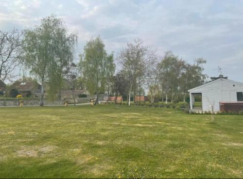 a large grass field with a white house in the background at Orchard Retreat - Rural Cabin - Private Hot Tub! in Gloucester