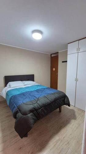 a bedroom with a bed with a blue blanket at Apartamento duplex a 1 cuadra de Playa Naplo in Pucusana