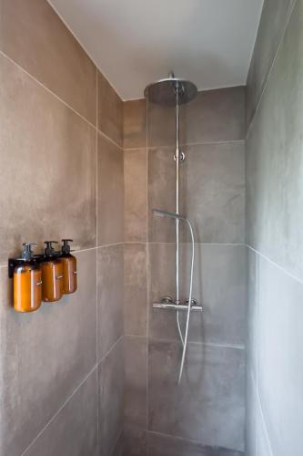 a bathroom with a shower with two containers on the wall at 6-p Wellnesshuisje met sauna/hottub bij Nijmegen in Ewijk