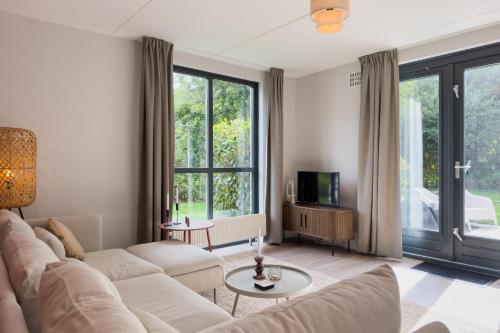 a living room with a couch and a tv at 6-p Wellnesshuisje met sauna/hottub bij Nijmegen in Ewijk