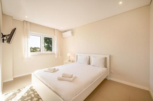 una camera da letto con un grande letto bianco con due asciugamani sopra di GuestReady - Sunshine oasis with pool ad Azeitao