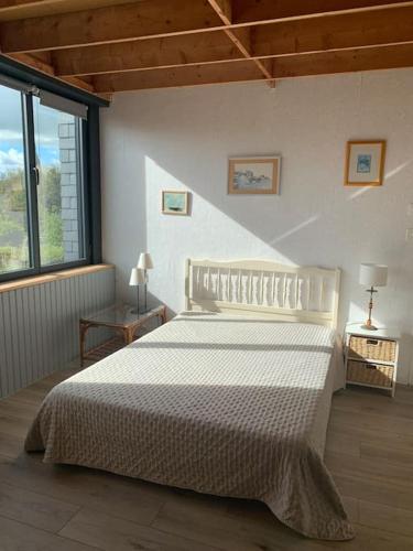 une chambre avec un lit blanc et une grande fenêtre dans l'établissement FileOVent, à Combrit