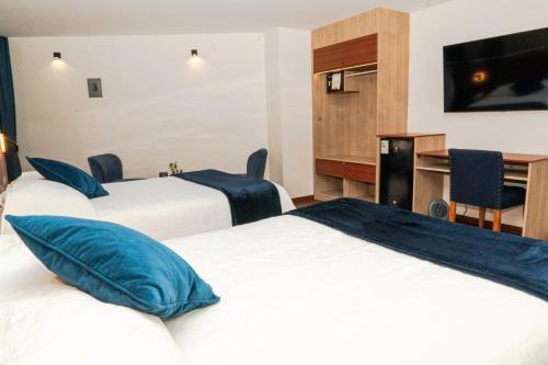 a hotel room with three beds and a television at Hotel Terra by Refugio Ecológico in Arequipa