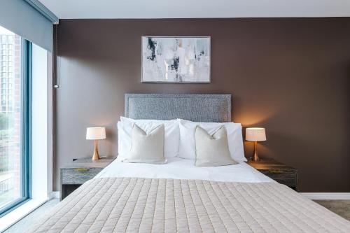a bedroom with a large white bed with two lamps at Stylish Leeds City Centre Flat - Free Parking in Leeds