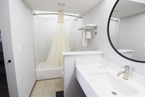 a white bathroom with a sink and a shower at Walnut Inn Roland in Roland
