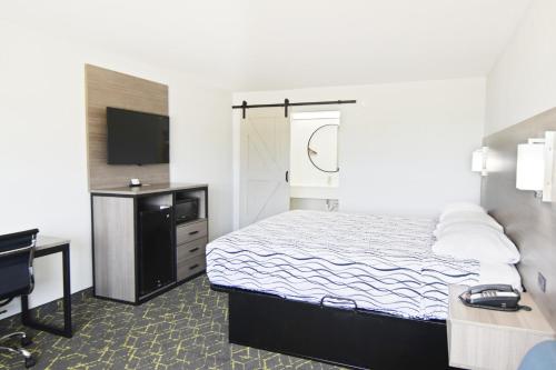 a bedroom with a bed and a desk and a television at Walnut Inn Roland in Roland