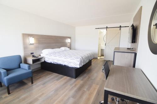 a hotel room with a bed and a blue chair at Walnut Inn Roland in Roland
