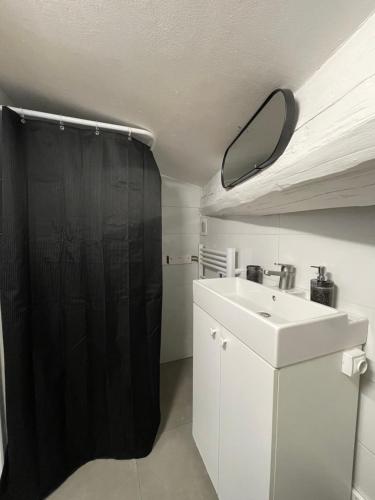 La salle de bains est pourvue d'un rideau de douche noir et d'un lavabo. dans l'établissement Asian Touch - A deux sous les toits, à Nîmes
