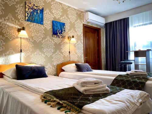 two beds in a hotel room with towels on them at Casa Topazz in Târgu Jiu