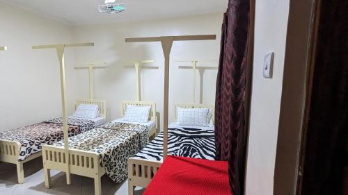 a room with two twin beds in a room at JACARANDA HOMESTAY in Moshi