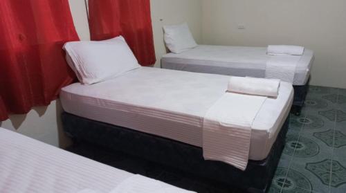 three beds in a room with red curtains at Chill House Flores in Flores
