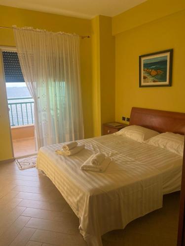 una camera da letto con un letto con lenzuola bianche e una finestra di Sunset Serenity Apartment a Durrës