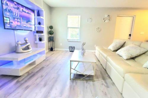 a living room with a white couch and a tv at Welcome to Tranquility House in Tampa