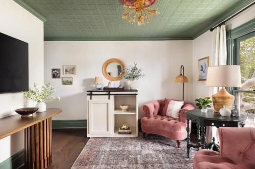 a living room with a pink chair and a mirror at Centrella Hotel, a Kirkwood Collection Hotel in Pacific Grove