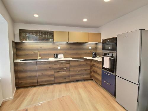 une cuisine avec des armoires en bois et un réfrigérateur dans l'établissement Gîte Alsacien pour 4 pers. rénové avec goût au cœur du vignoble, route des Vins, Gueberschwihr. - FR-1-722-9, à Gueberschwihr