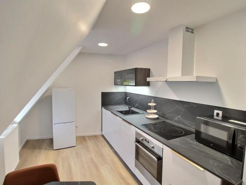 une cuisine avec un comptoir noir et un four micro-ondes dans l'établissement Gîte rénové de charme à Gueberschwihr, au cœur du vignoble, idéal pour 2 personnes - FR-1-722-10, à Gueberschwihr