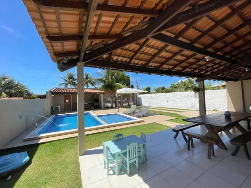 eine Terrasse mit Tisch und Stühlen und einem Pool in der Unterkunft Casa de Praia em Maceió AL - 100m da praia in Maceió