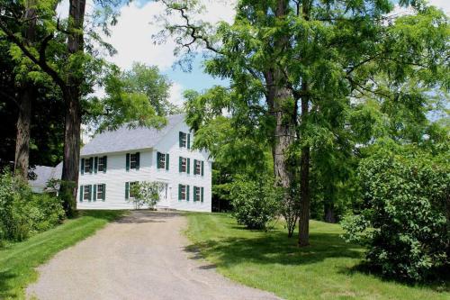 a white house with a dirt road in front at The Dutton Farmhouse in Dummerston Center