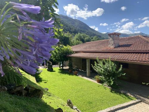 a house with a yard with a purple flower at Casa do Fijogo no Gerês avec Piscine in Rio Caldo