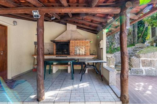 a patio with a table and an outdoor fireplace at Casa do Fijogo no Gerês avec Piscine in Rio Caldo