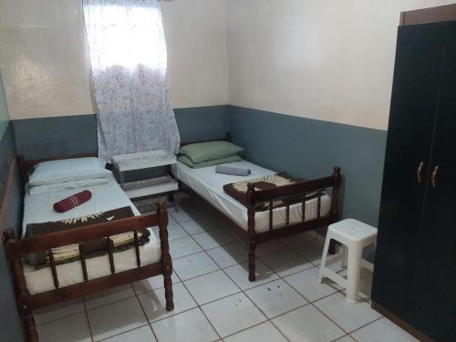 a small room with two beds and a window at Vivendas do Trabalhador in São Francisco do Sul