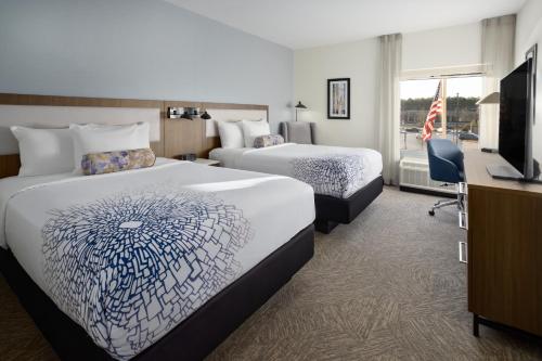 a hotel room with two beds and a desk at La Quinta Inn & Suites by Wyndham Locust Grove in Locust Grove