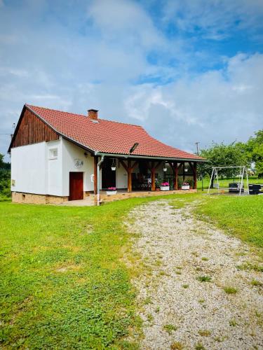 a building with a playground in front of a field at Őrségi Szajkó Vendégház in Kondorfa
