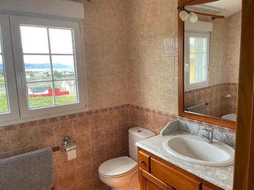 a bathroom with a sink and a toilet and a mirror at Casa Playa Fontela in San Pedro de Benquerencia