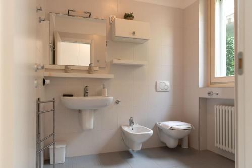 une salle de bain avec un lavabo, des toilettes et un miroir dans l'établissement Sant'Anna Villetta Giardino - Pianello del Lario by LoveComo, à Pianello Del Lario