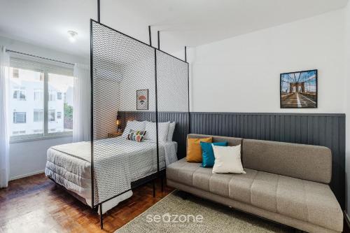 a bedroom with a bed and a couch at Studio Confortável e Bem Localizado em POA CEI0304 in Porto Alegre