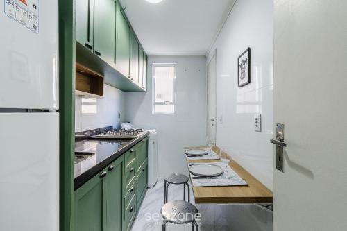 a kitchen with green cabinets and a table in it at Studio Confortável e Bem Localizado em POA CEI0304 in Porto Alegre